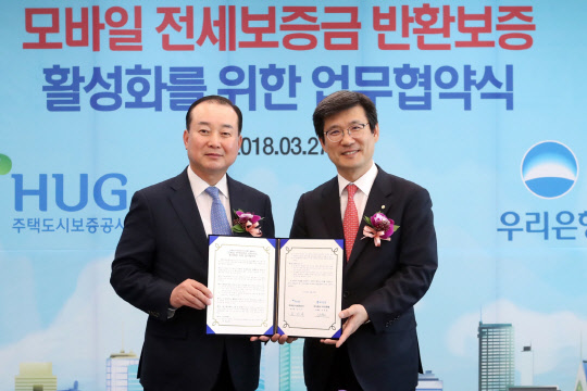 27일 서울 중구 우리은행 본점에서 진행된 '우리은행-주택도시보증공사, 모바일 전세보증금 반환보증 활성화를 위한 업무협약식'에서 김기돈 주택도시보증공사 금융사업본부 본부장(왼쪽)과 이창재 우리은행 부동산금융그룹 그룹장이 기념촬영을 하고 있다.  우리은행 제공